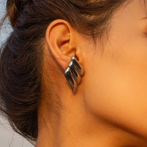 Minimalist silver wing-shaped stainless steel earrings on model in macro view