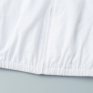 Detail shot of the central zipper closure and elastic hem on the white vest top