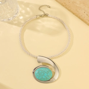 Silver woven necklace with irregular pendant and turquoise stone on a flat lay setting