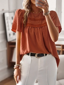Detail view of reddish brown round neck top featuring lace stitching and polka dot texture
