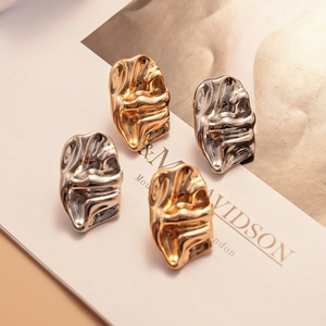 Irregular wrinkled metal stud earrings in gold and silver with lava texture finish