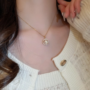 Gros plan d'un collier doré élégant avec pendentif en perle entouré de zircons brillants