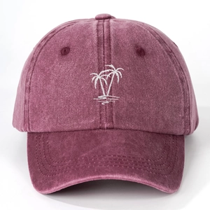 Close-up of coconut tree embroidery on a vintage washed cotton baseball cap in burgundy