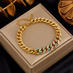 Close-up of gold Cuban chain bracelet featuring blue evil eye charms and s.steel tag