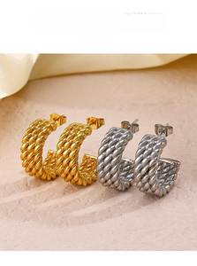 Detail showing high-texture gold and silver braided rope twist hoop earrings on stone
