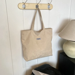 Close-up of beige corduroy tote bag showing striped texture hanging on a wall hook