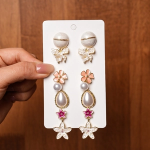 Close-up of floral and pearl earrings set featuring gold finish and enamel details