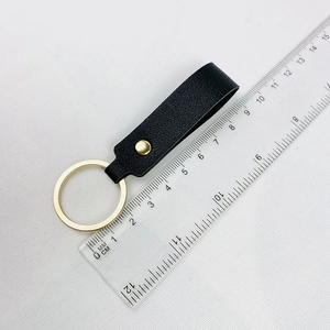Minimalist black PU leather keychain with gold metal ring and buckle next to a ruler