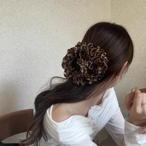 Detail einer großen Haarspange mit Leopardenmuster-Stoffblume im Haar