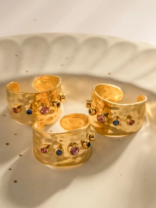 Detailansicht von drei goldenen Hammerschlag-Ringen mit bunten Edelsteinen in Schale