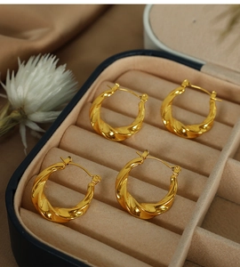 Vue macro de deux paires de créoles torsadées plaquées or 18 carats dans un écrin en velours