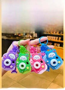 Detailed close-up of cartoon bear projection camera keychain available in four vibrant colors