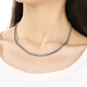 Gros plan d'un collier chaîne en os de dragon argenté porté par un mannequin