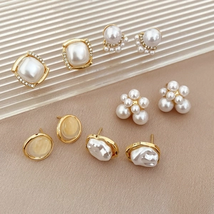 Close-up of five elegant pearl and crystal stud earrings in a luxury gold finish