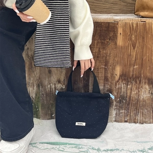 Close-up of navy polka dot wool handbag with drawstring and woven label detail