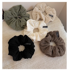 Close-up of knit scrunchies with diamond texture and decorative fabric labels