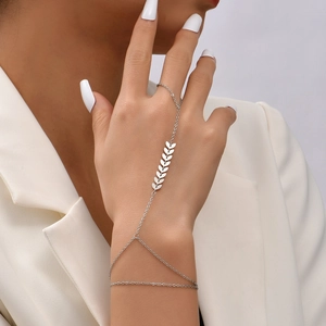 Detailed view of silver leaf charm finger ring bracelet worn on hand with white blazer