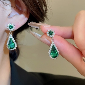 Detail view of water drop green gemstone earrings with diamond halo on silver base
