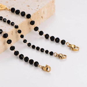 Minimalist black beaded necklace and bracelet with gold lobster clasp on white stone