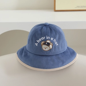 Détail d'un chapeau bob enfant en velours bleu avec broderie ours et texture douce