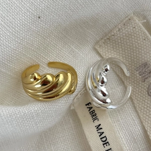 Minimalist croissant rings in gold and silver finish on a white textured fabric background