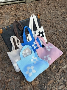 Knitted flower pattern tote bags in various colors displayed on a chair outdoors