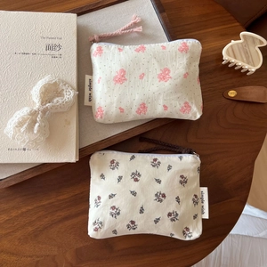 Close-up of floral print cotton mini storage pouches with zippers and woven cord details