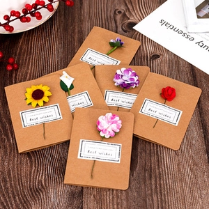 Close-up of handmade kraft paper greeting cards with colorful artificial flowers and tags