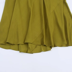 Detail view of mustard green satin dress featuring asymmetric hemline and silky texture