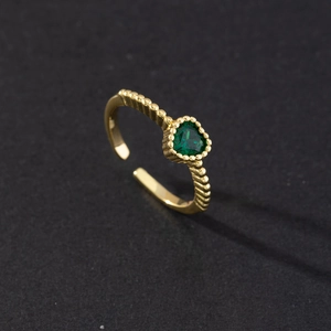 Detail of heart-shaped emerald green stone on gold beaded texture adjustable ring