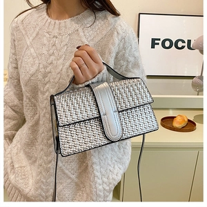 Detail of silver metallic woven handbag with crossbody strap against a stylish backdrop