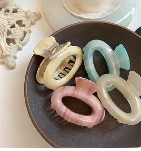 Detail of four colorful acetate hair claws in a ceramic bowl with elegant marble decor