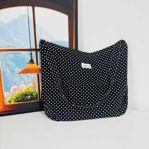 Close-up of black floral canvas tote bag with white polka dots and woven brand label