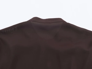 Dettaglio del collo posteriore e della cucitura della spalla di una camicia scura
