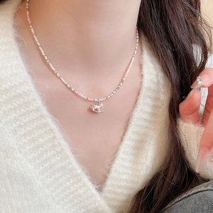 Gros plan d'un collier de perles roses avec pendentif cheval à bascule sur le cou