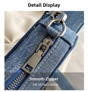 Macro detail of silver metal zipper and washed blue denim texture on crossbody bag