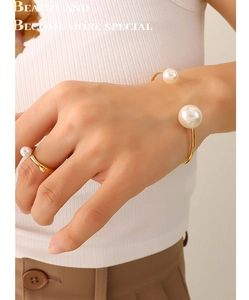 Detailed view of elegant gold-plated open pearl bracelet and matching ring on model