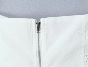 Détail de la dentelle fleurie blanche et fermeture éclair invisible sur le gilet