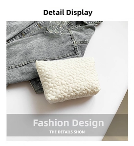 Detail view of cream quilted clutch with 3D floral textures on denim background