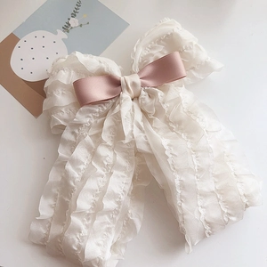 Detail of beige chiffon ruffled bow hair clip with pink center in French vintage style