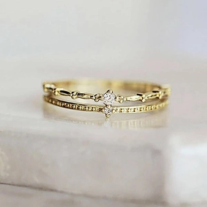 Détail macro d'une bague dorée double couche avec perles et une pierre en zircone brillante