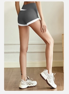 Detail showing high-waisted gray yoga shorts with white trim and butt-lifting seam