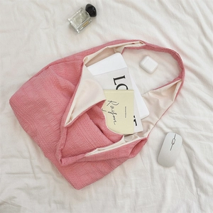Pink pleated tote bag showing large capacity for laptop and books in a lifestyle setting