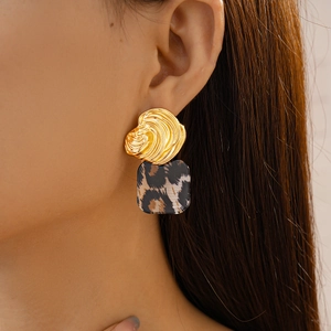 Close-up of leopard print resin square pendant and golden spiral metal earring on model