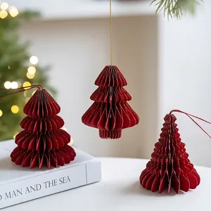 Three red paper honeycomb Christmas tree ornaments with gold glitter edges and red strings
