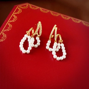 Detailed close-up of double-layer zircon and imitation pearl tassel earrings on red box