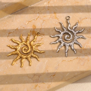 Detail of sun pendant charms in gold and silver finish with spiral texture on stone background