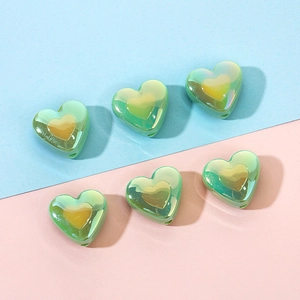 Macro shot of two-tone gradient green heart beads with metallic gold center for DIY crafts