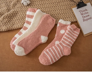 Detailed texture of thick pink coral fleece socks featuring soft stripes and polka dots