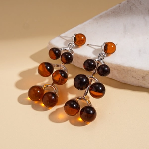 Macro detail of long resin drop earrings with brown beads on textured stone base